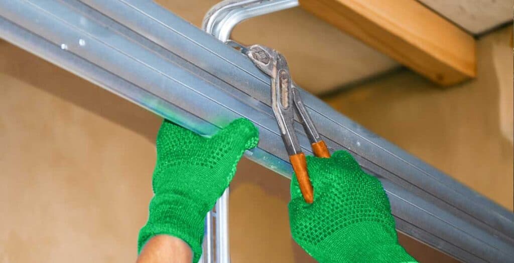 Garage door repairman fixing a bent track.
